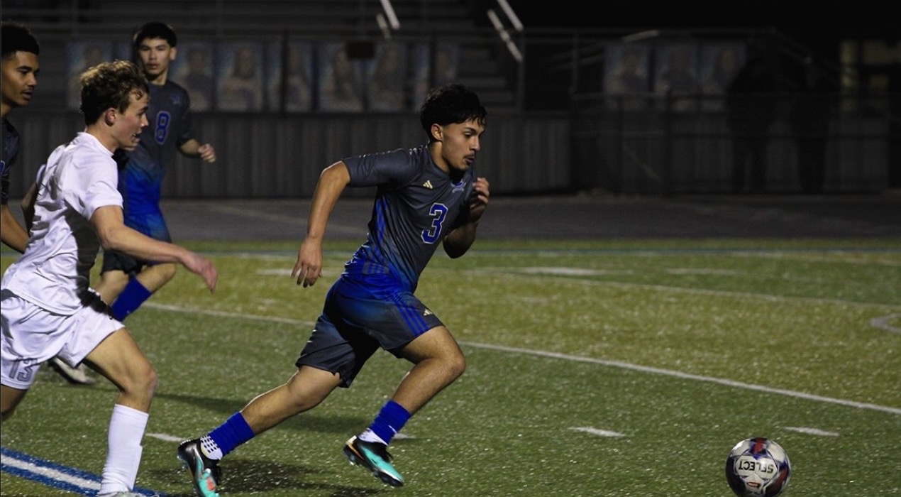 Soccer player sprinting with the ball during a night match