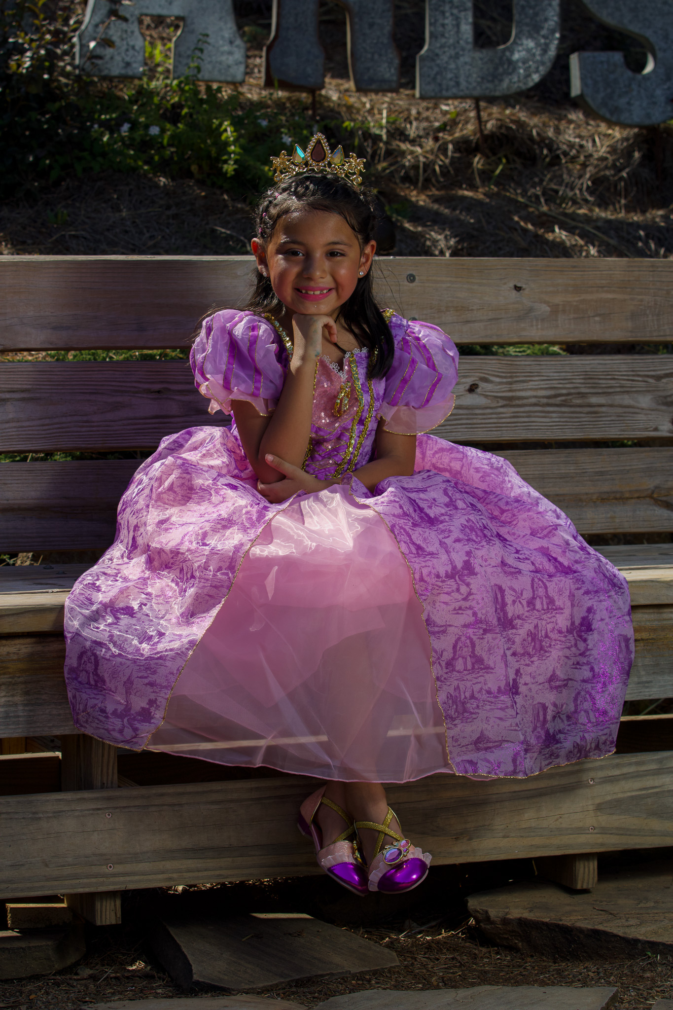 Young princess in a purple gown seated on a wooden bench