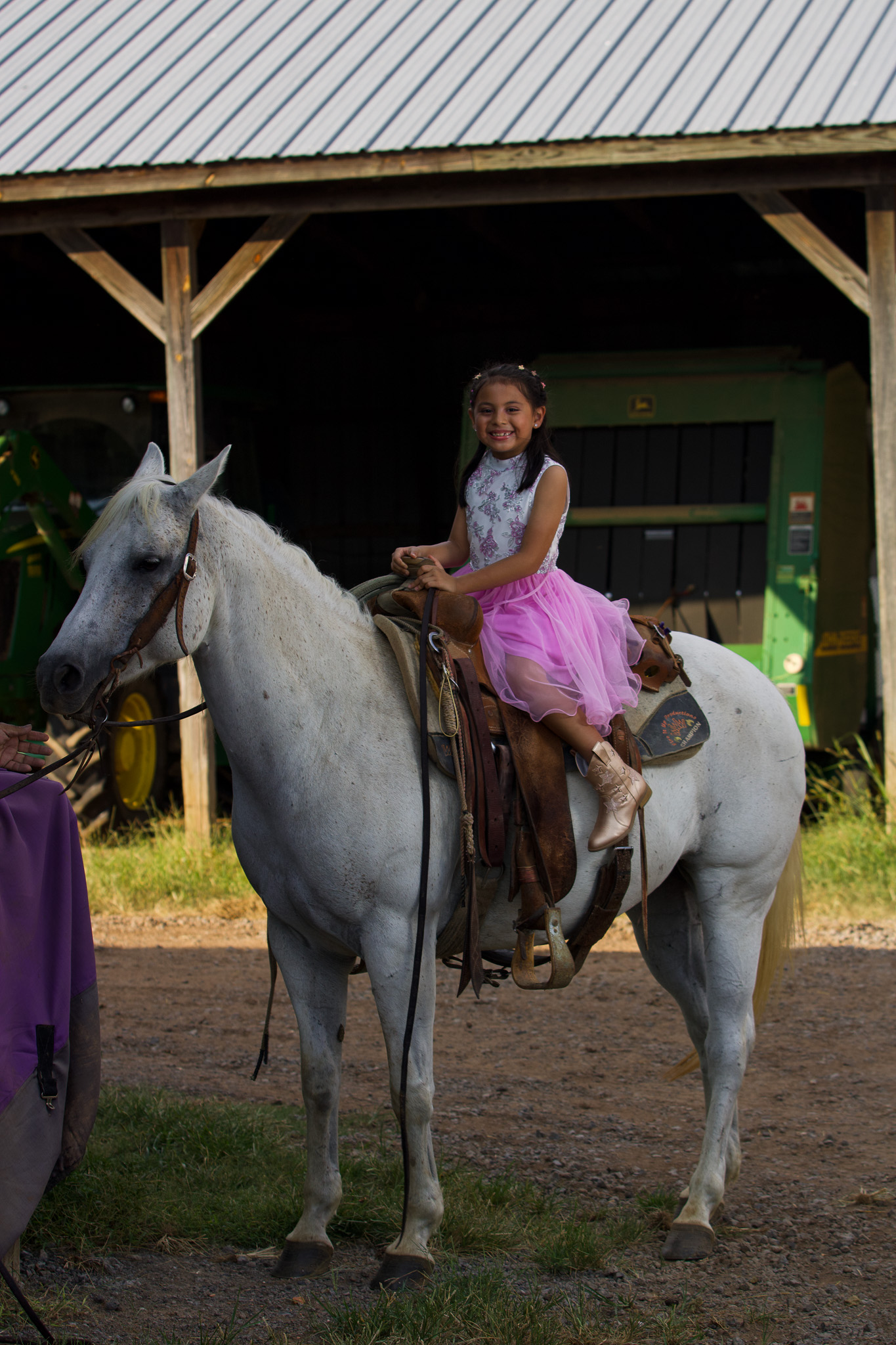 Young girl in a purple gown riding a white horse