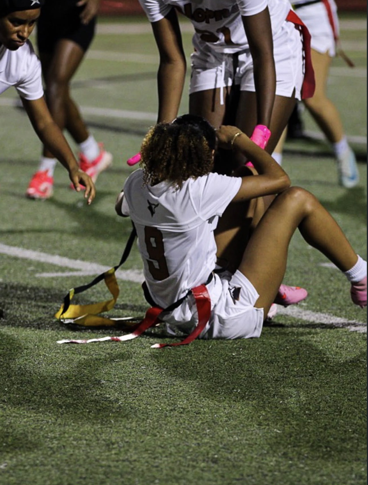 Flag football player seated on the field after a play