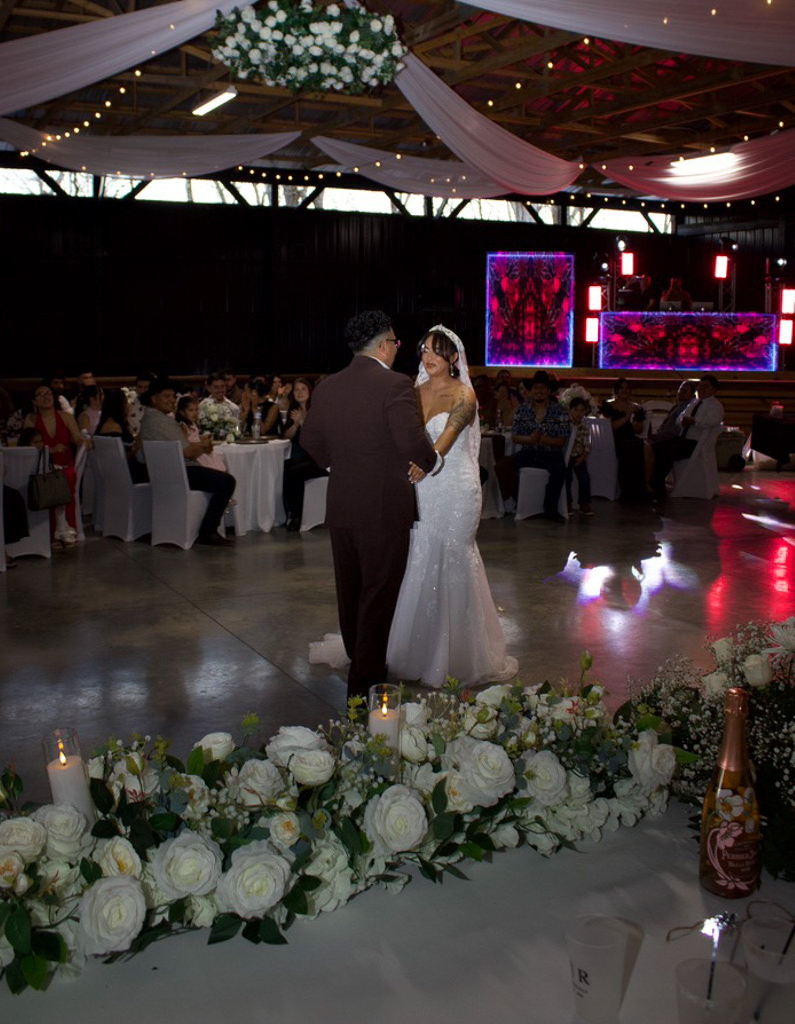 A newlywed couple dancing beneath reception lights